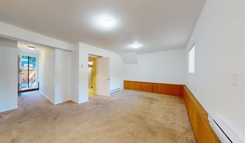 Spare room featuring baseboard heating, light carpet, and a baseboard heating unit