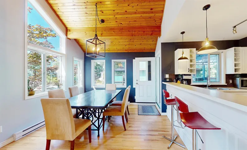Dining room featuring a baseboard heating unit, light wood-style flooring, healthy amount of natural light, vaulted ceiling, and wood ceiling