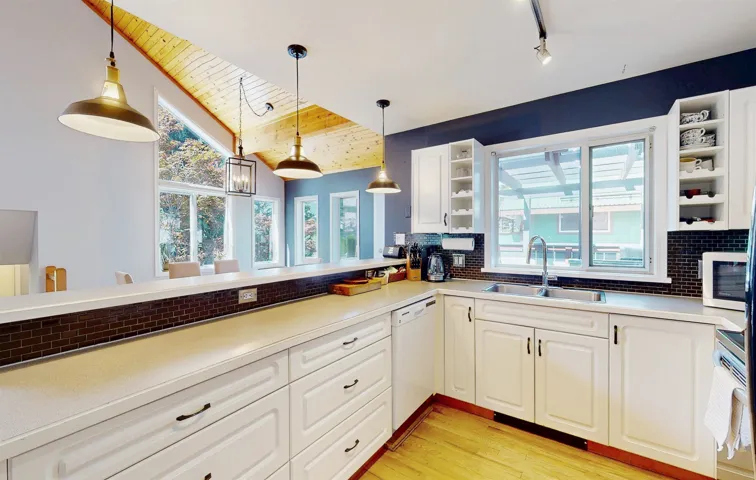 Kitchen with dishwasher, backsplash, light countertops, pendant lighting, and wooden ceiling
