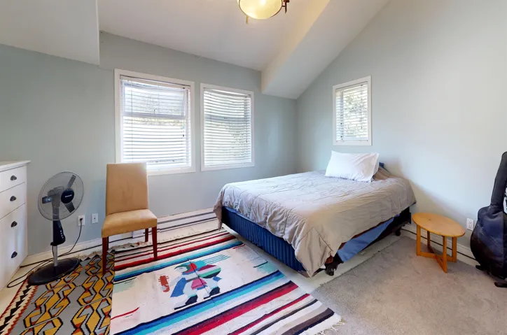 Bedroom featuring light colored carpet and vaulted ceiling