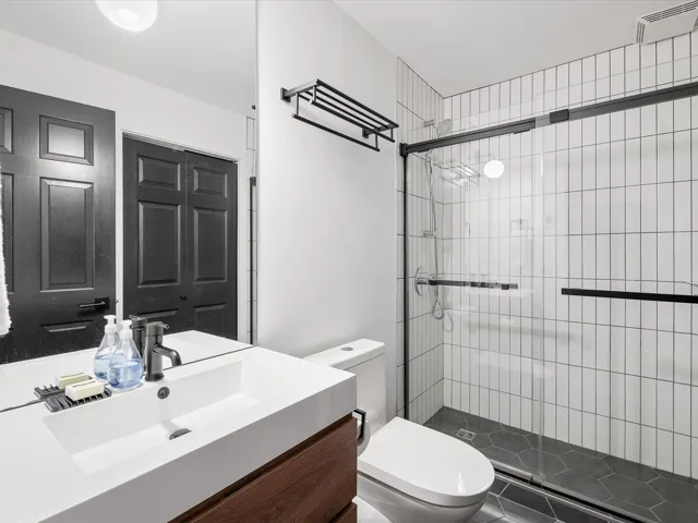 Bathroom with toilet, a stall shower, and vanity