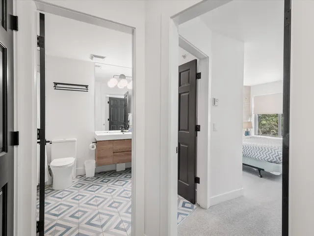 Ensuite bathroom with visible vents, baseboards, toilet, vanity, and ensuite bath