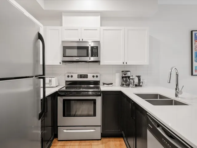 Kitchen with white cabinetry, appliances with stainless steel finishes, light countertops, and a sink