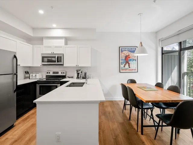Kitchen featuring white cabinets, a sink, appliances with stainless steel finishes, a peninsula, and backsplash