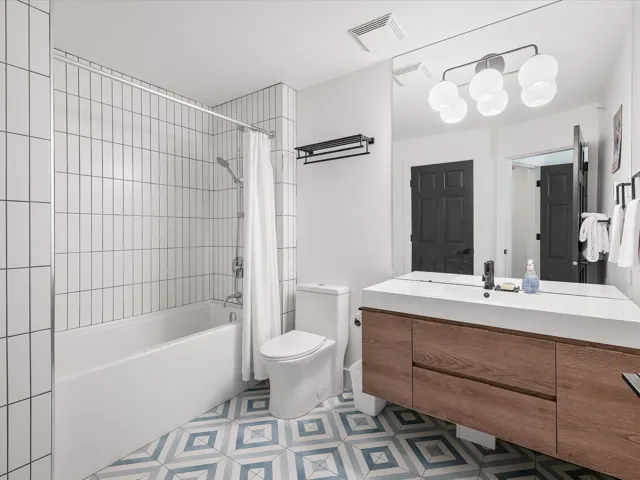 Full bathroom featuring visible vents, shower / tub combo with curtain, toilet, and vanity