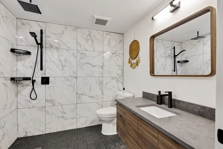 Bathroom featuring vanity, a marble finish shower, and tile patterned flooring