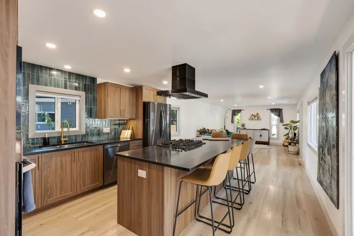 Kitchen featuring extractor fan, appliances with stainless steel finishes, dark countertops, a breakfast bar, and recessed lighting