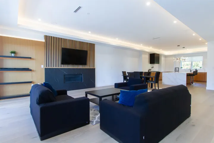 Living room featuring a premium fireplace, a notable chandelier, visible vents, a raised ceiling, and light wood-style floors