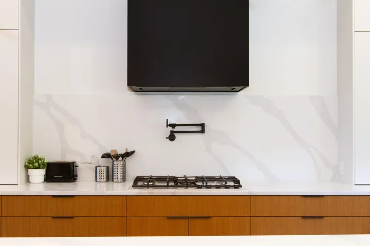 Detailed view of pot filler, light countertops, and modern cabinets