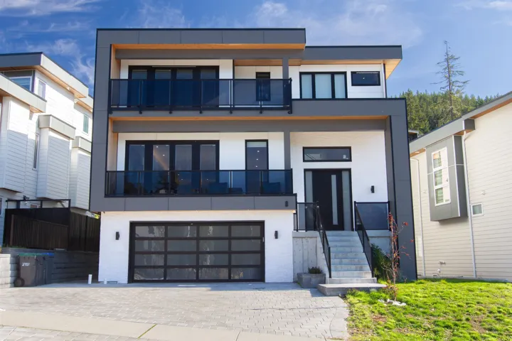 Contemporary house featuring a balcony, stucco siding, an attached garage, and decorative driveway