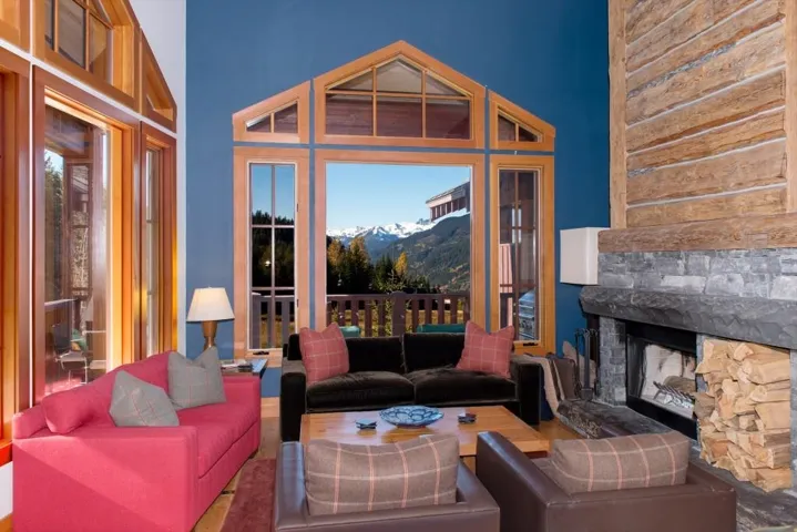 Living room with a mountain view, a stone fireplace, a towering ceiling, and wood finished floors