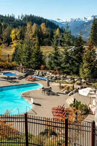 Community pool featuring a patio, a community hot tub, a view of trees, and a mountain view