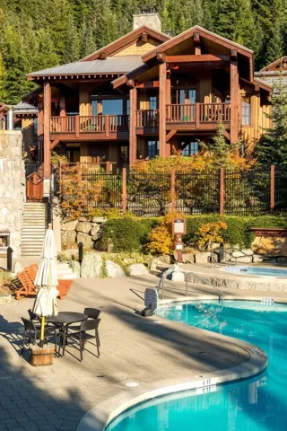 Rear view of house featuring a balcony, a patio area, a chimney, a community pool, and a forest view