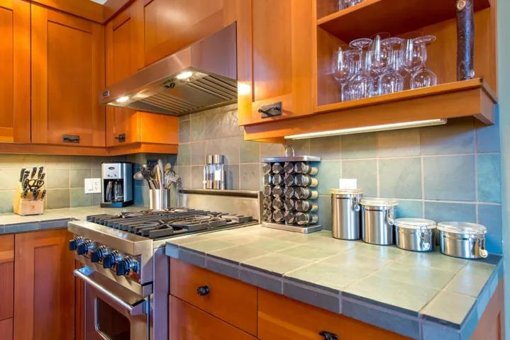 Kitchen with under cabinet range hood, stainless steel stove, and backsplash