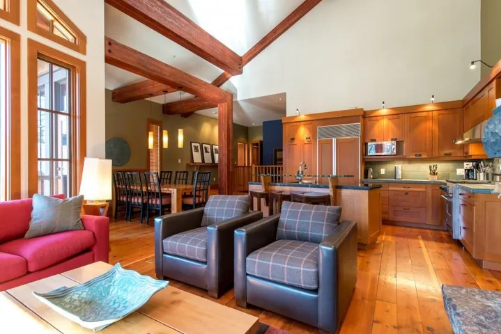 Living area featuring light wood-style floors, beamed ceiling, and a high ceiling
