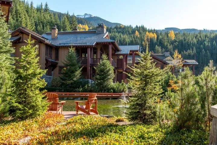 Rear view of house featuring a chimney, a wooded view, a balcony, and a water and mountain view