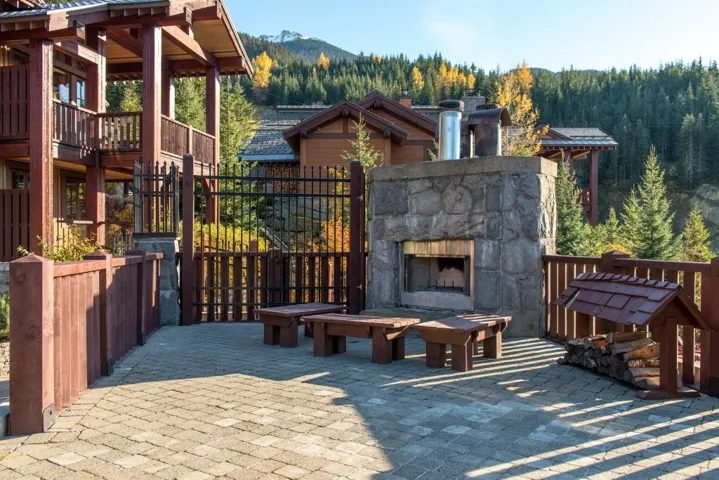 View of patio / terrace with an outdoor stone fireplace, a forest view, and a mountain view