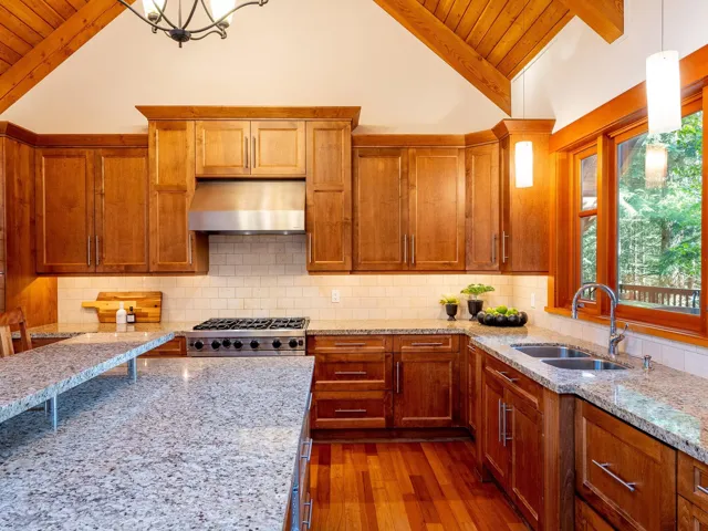 Kitchen featuring decorative light fixtures, light stone countertops, brown cabinets, and wooden ceiling