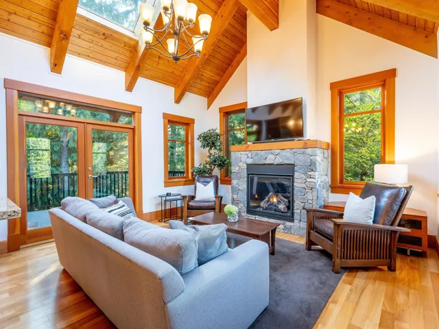 Living room featuring a wooden ceiling with exposed beams, high vaulted ceiling, a chandelier, light wood-style flooring, and a fireplace