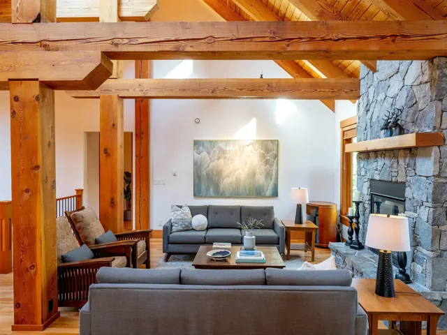 Living area featuring wood finished floors, high vaulted ceiling, a stone fireplace, and a wood ceiling with exposed beams