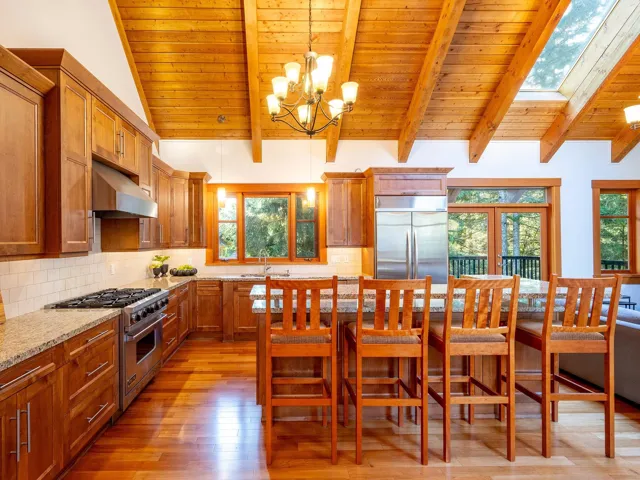 Kitchen with brown cabinets, wooden ceiling, backsplash, and stainless steel appliances