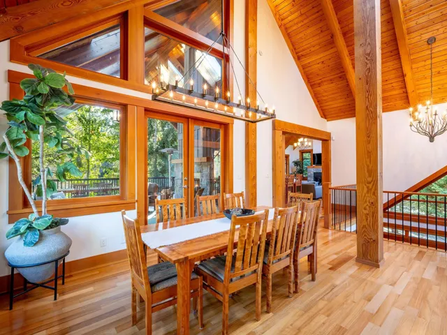 Dining space featuring high vaulted ceiling, light wood finished floors, healthy amount of natural light, a wood ceiling with exposed beams, and a chandelier