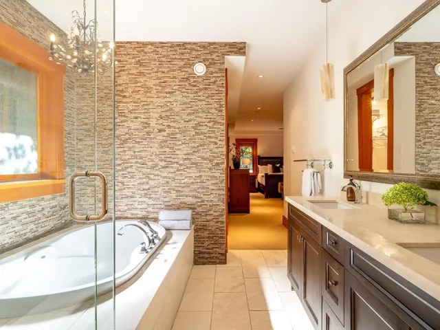 Ensuite bathroom featuring double vanity, a bath, light tile patterned floors, a chandelier, and recessed lighting