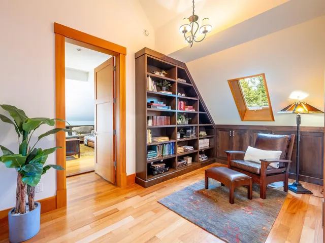 Living area with vaulted ceiling, light wood finished floors, a skylight, and a chandelier