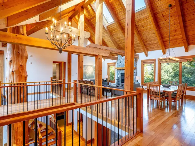 Interior space featuring a chandelier, light wood finished floors, high vaulted ceiling, a wood ceiling with exposed beams, and a skylight