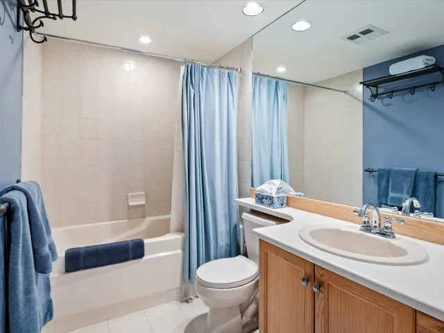 Full bath featuring vanity, tile patterned flooring, toilet, shower / bathtub combination with curtain, and visible vents