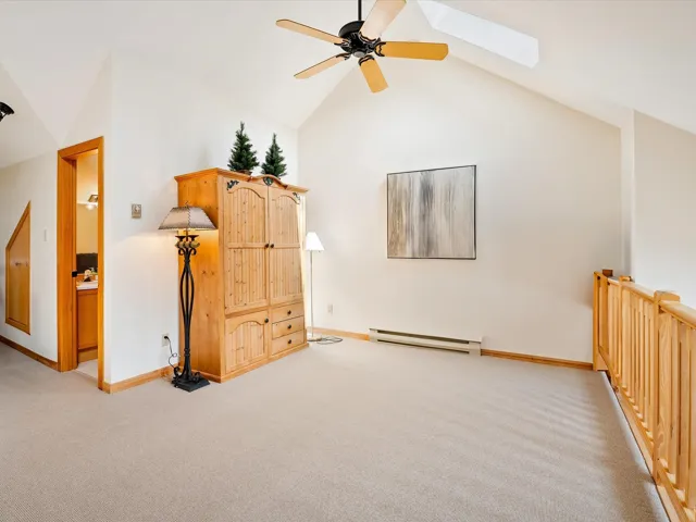 Bonus room with light carpet, high vaulted ceiling, and a baseboard heating unit