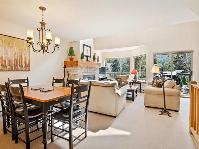 Dining space featuring light colored carpet, a fireplace, a notable chandelier, and plenty of natural light