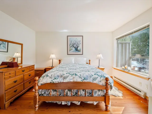 Bedroom with wood-type flooring and a baseboard heating unit