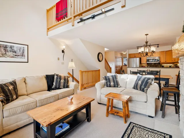 Living room featuring light carpet, stairs, a towering ceiling, and an inviting chandelier