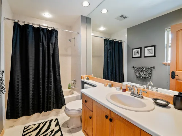 Bathroom featuring vanity, shower / bath combo, tile patterned floors, toilet, and visible vents