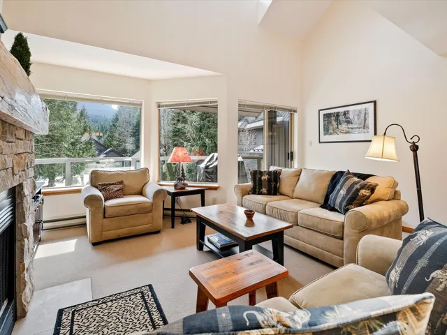 Carpeted living area featuring a baseboard radiator, a towering ceiling, and a fireplace
