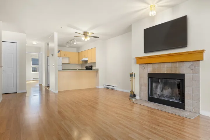 Unfurnished living room with light wood-style flooring, baseboards, baseboard heating, and a tile fireplace