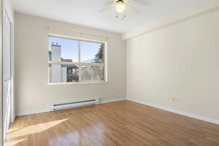 Spare room with a baseboard heating unit, ceiling fan, baseboards, and wood finished floors