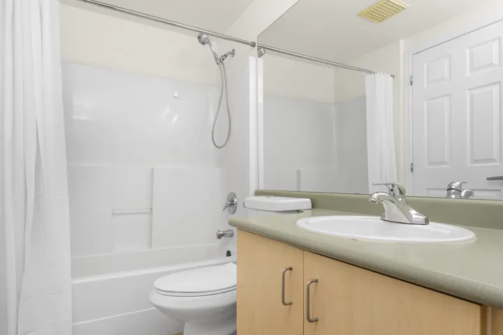 Full bathroom featuring toilet, shower / tub combo, vanity, and visible vents