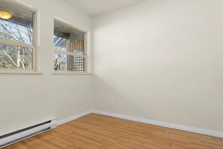 Unfurnished room with a baseboard heating unit, light wood-style floors, a wealth of natural light, and baseboards