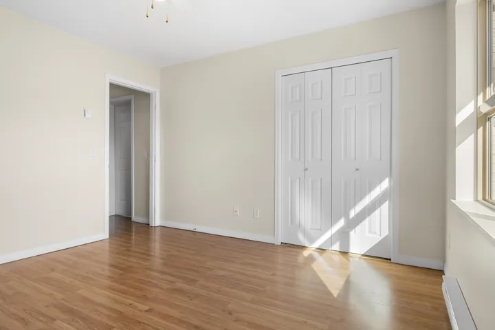 Unfurnished bedroom featuring a closet, wood finished floors, and baseboards