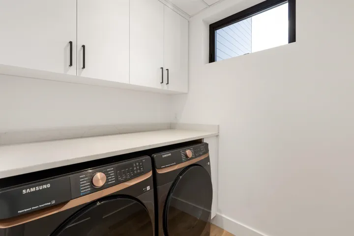 Laundry area featuring wood finished floors, washing machine and dryer, and cabinet space