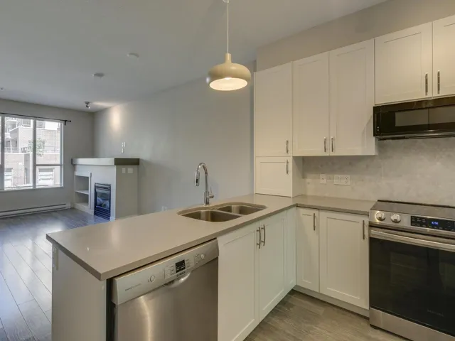 Kitchen featuring appliances with stainless steel finishes, wood finished floors, a peninsula, white cabinets, and backsplash