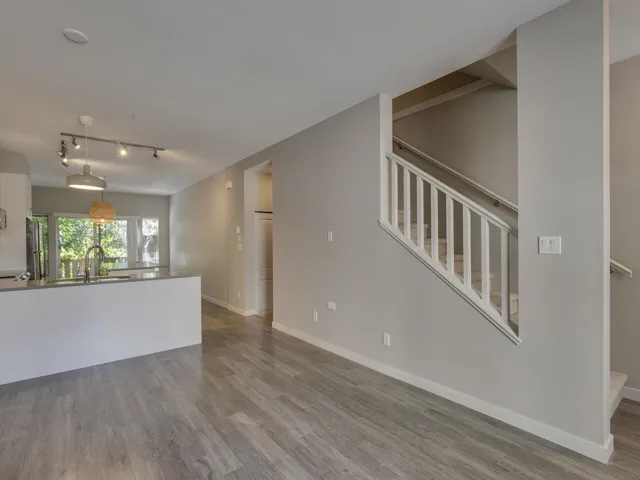 Unfurnished living room featuring stairway, rail lighting, and wood finished floors