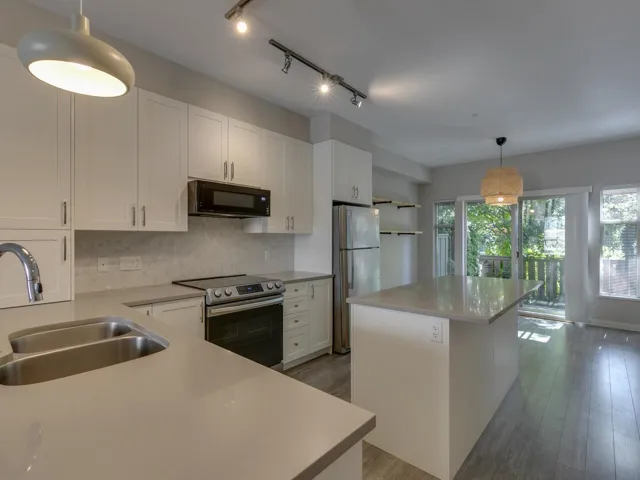 Kitchen with electric range, a kitchen island, tasteful backsplash, dark wood-type flooring, and freestanding refrigerator