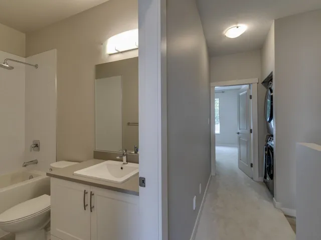 Full bathroom featuring stacked washer / dryer, vanity, and bathtub / shower combination