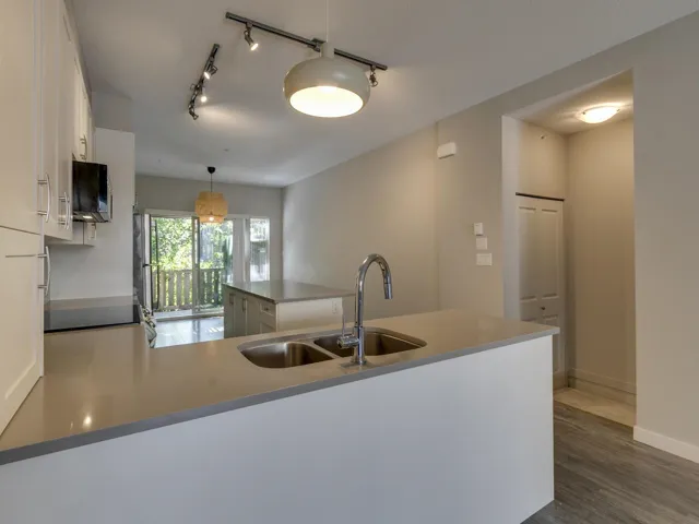 Kitchen with white cabinetry, dark wood-style floors, hanging light fixtures, a peninsula, and a kitchen island