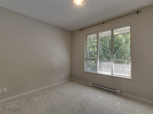 Carpeted spare room with a baseboard radiator and baseboards
