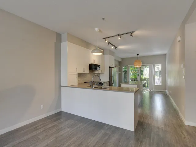 Kitchen featuring dark wood finished floors, white cabinetry, a peninsula, hanging light fixtures, and track lighting