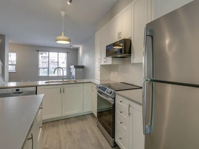 Kitchen with stainless steel appliances, white cabinets, light wood-style floors, and tasteful backsplash